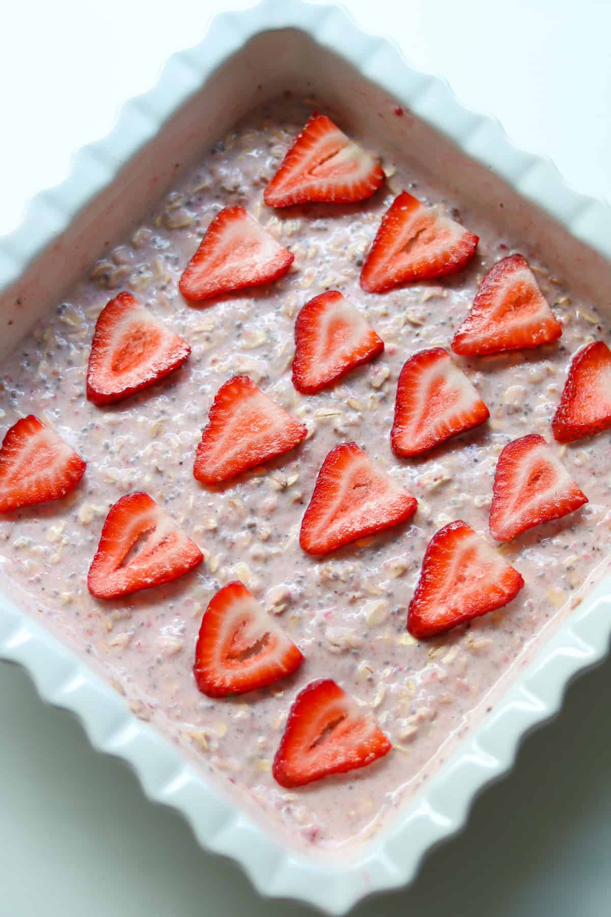 The oatmeal mixture with topped strawberries in a baking dish.