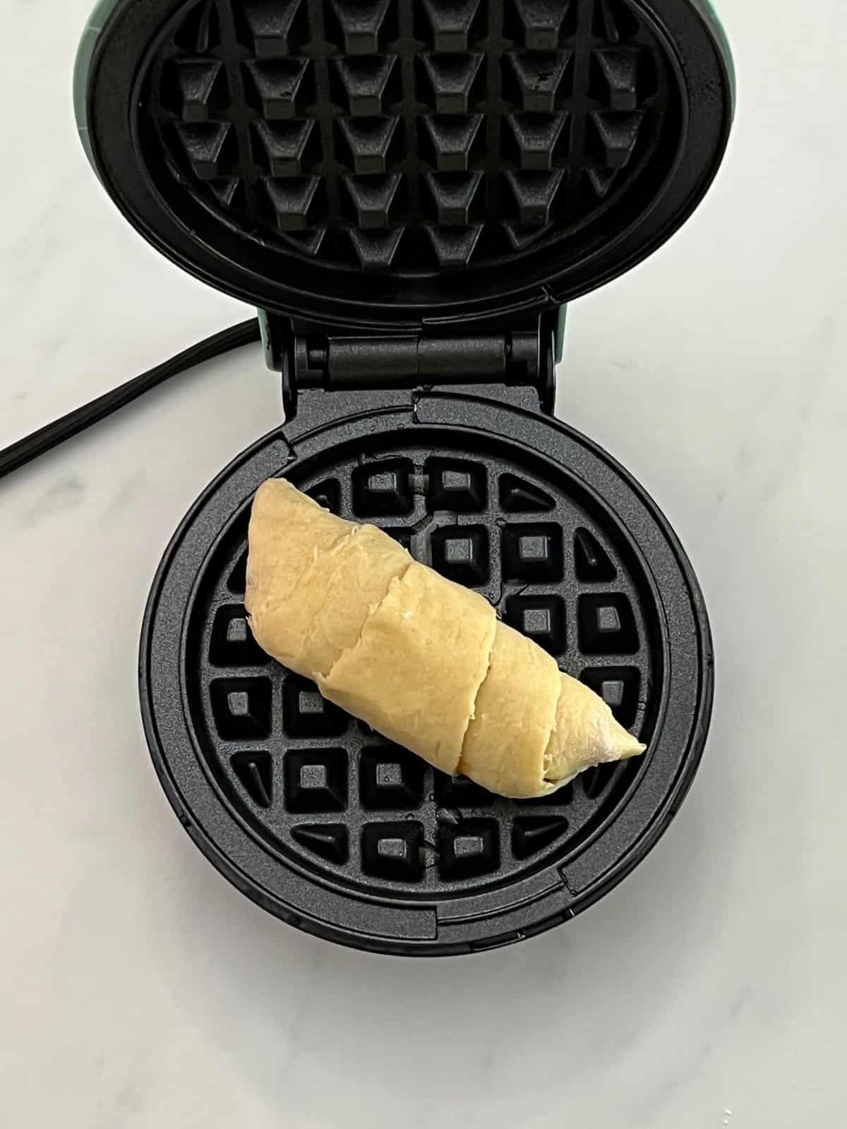 Crescent roll placed in waffle iron.